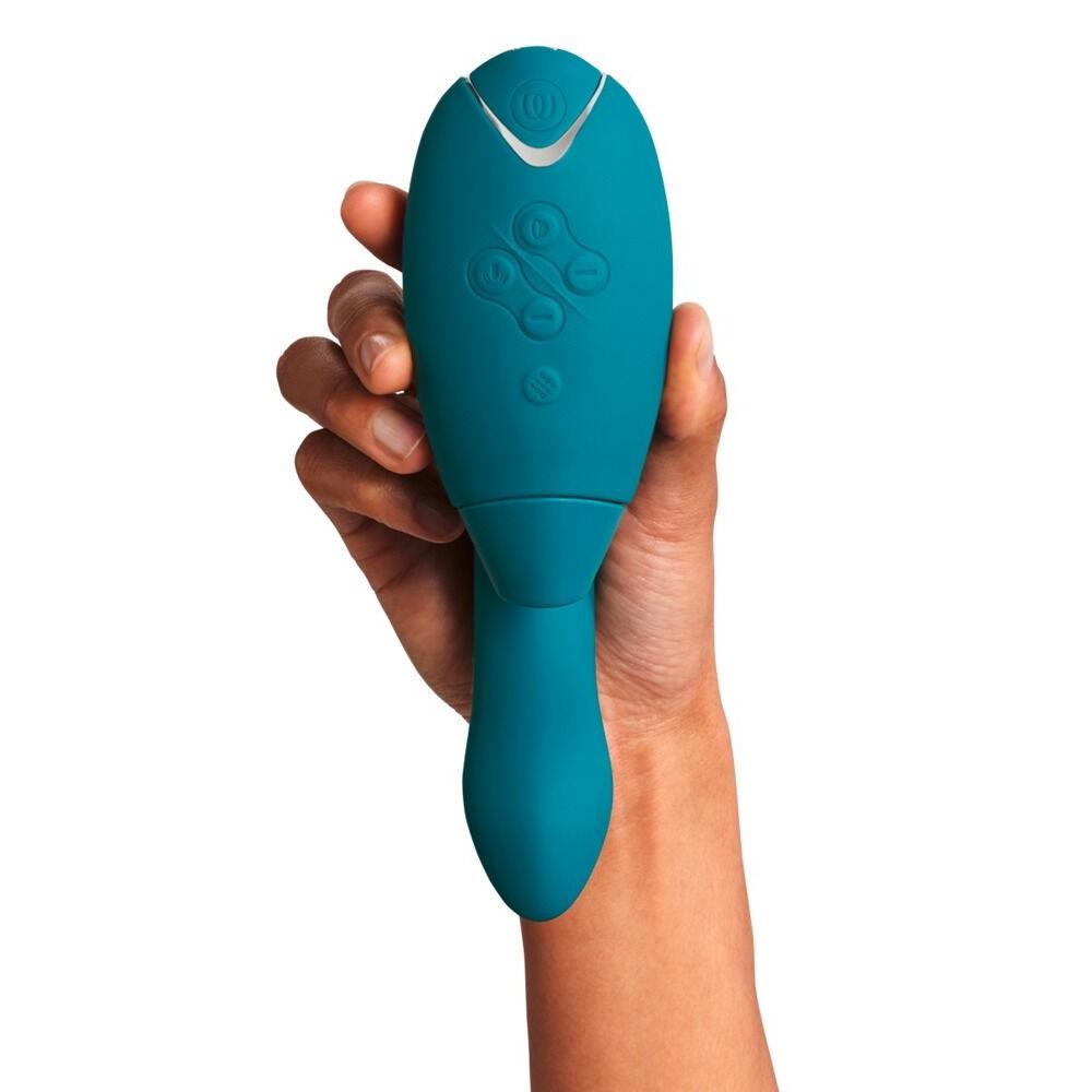 Hånd holder en dyp grønn Womanizer DUO 2 rabbitvibrator med sølvfargede knapper.