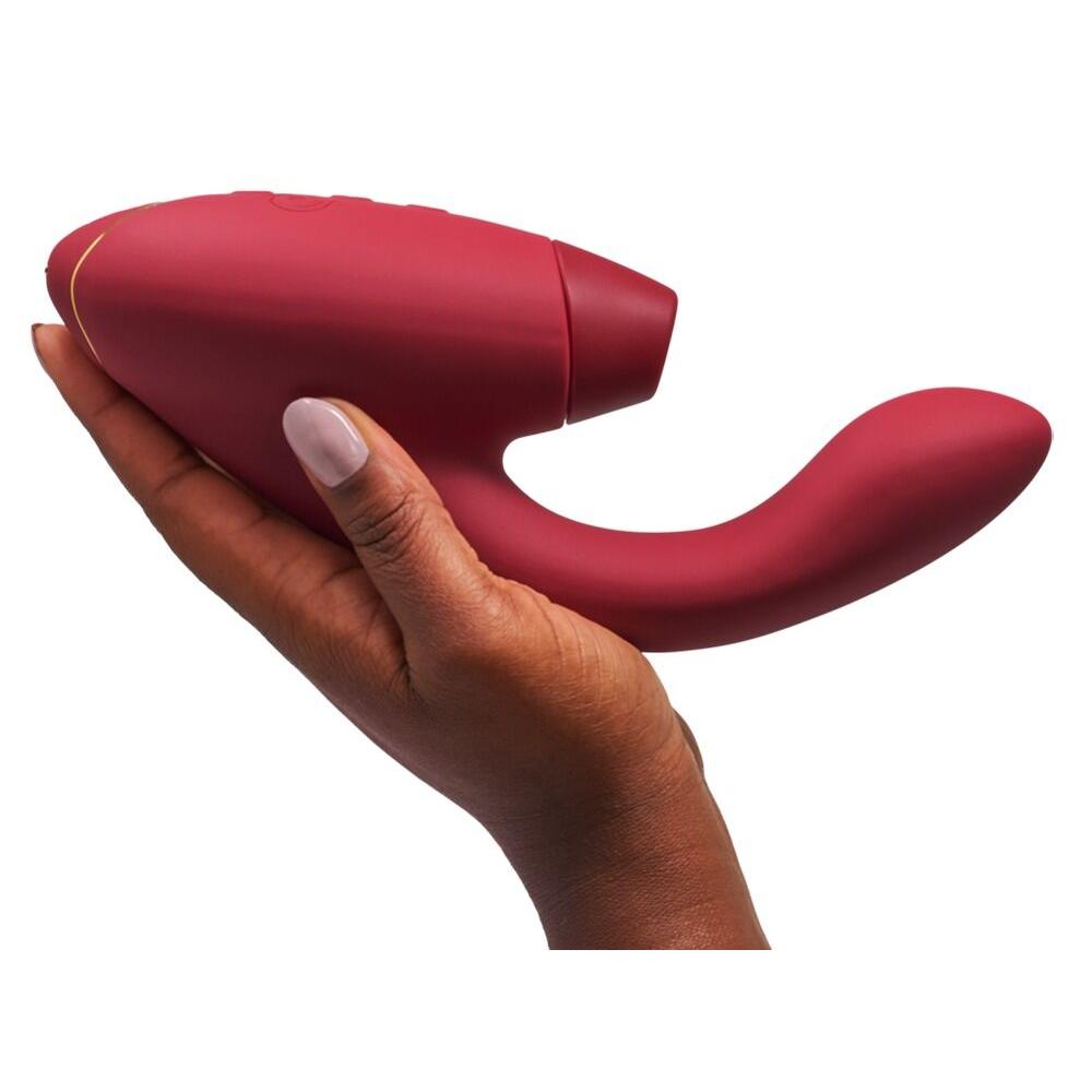 Dyp rød Womanizer Duo 2 klitoris- og G-punktstimulator i silikon, holdt i en hånd.