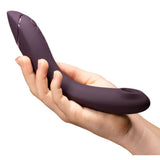 Womanizer OG G-punktvibrator i burgunderrød silikon, holdt i en hånd, med Pleasure Air-teknologi.