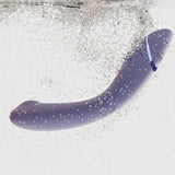 Womanizer OG vibrator i lilla, buet design, nedsenket i vann med bobler.