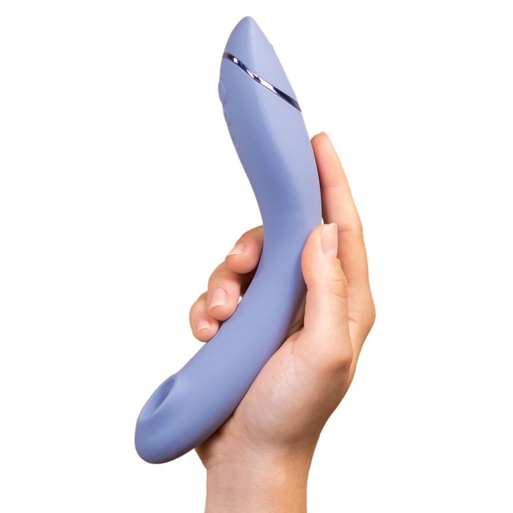 Hånd holder en lilla Womanizer OG G-punktvibrator med Pleasure Air-teknologi og elegant metallisk detalj.
