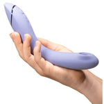 Womanizer OG vibrator i lilla silikon, holdt i en hånd, med Pleasure Air-teknologi og kontrollknapper.