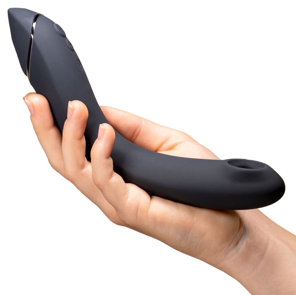 Hånd holder en Womanizer OG G-punktvibrator i matt sort silikon med metallisk detalj og buet design.