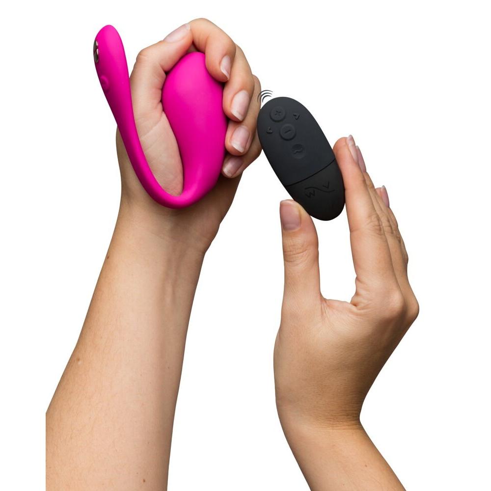 Hender holder en rosa, kurvet We-Vibe Jive 2 vibrator og en svart fjernkontroll.