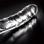 Klar, håndlaget glassdildo med elegant, bølget design og glatt overflate for temperaturlek.