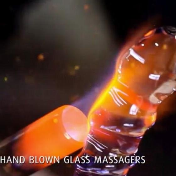 Håndblåst glassdildo med bølgete form og perlede kuler, glødende varm under produksjon.