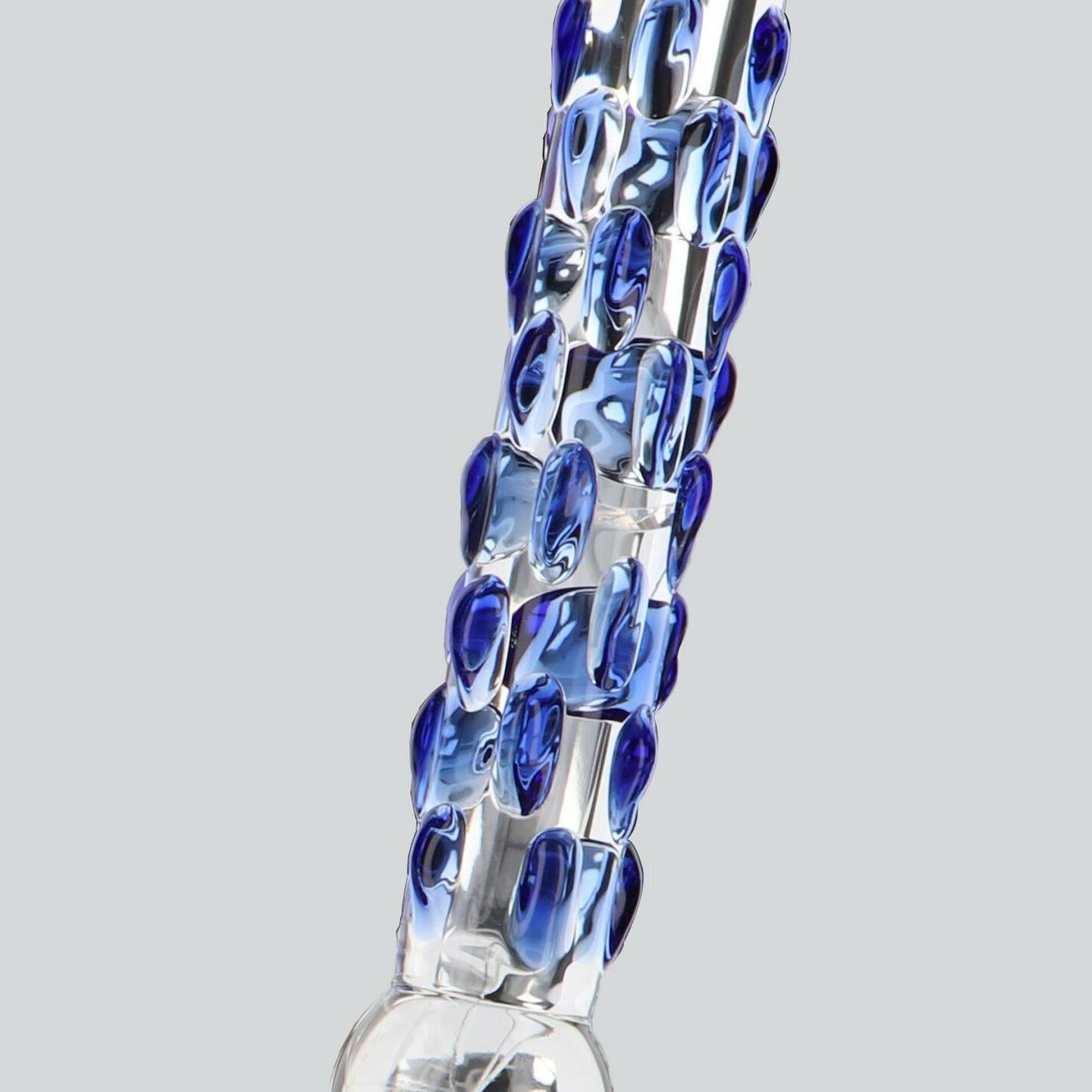 Klar glassdildo med buet silhuett og blå stimuleringsknopper.