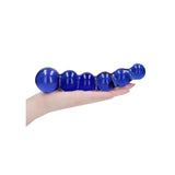 Hånd holder en blå, strukturert glassdildo med kuler, egnet for temperaturlek.