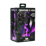 Grim Fantasy Dildo i lilla og svart silikon, med taggete pigger og riller, i en mørk eske.