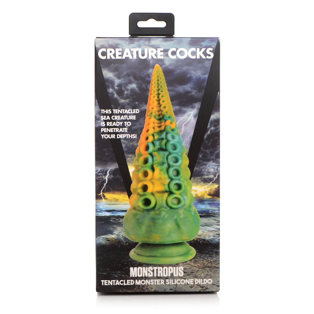 Marmored grønn, blå og gul tentakeldildo med sugekopper, vist i esken med "CREATURE COCKS" logo.
