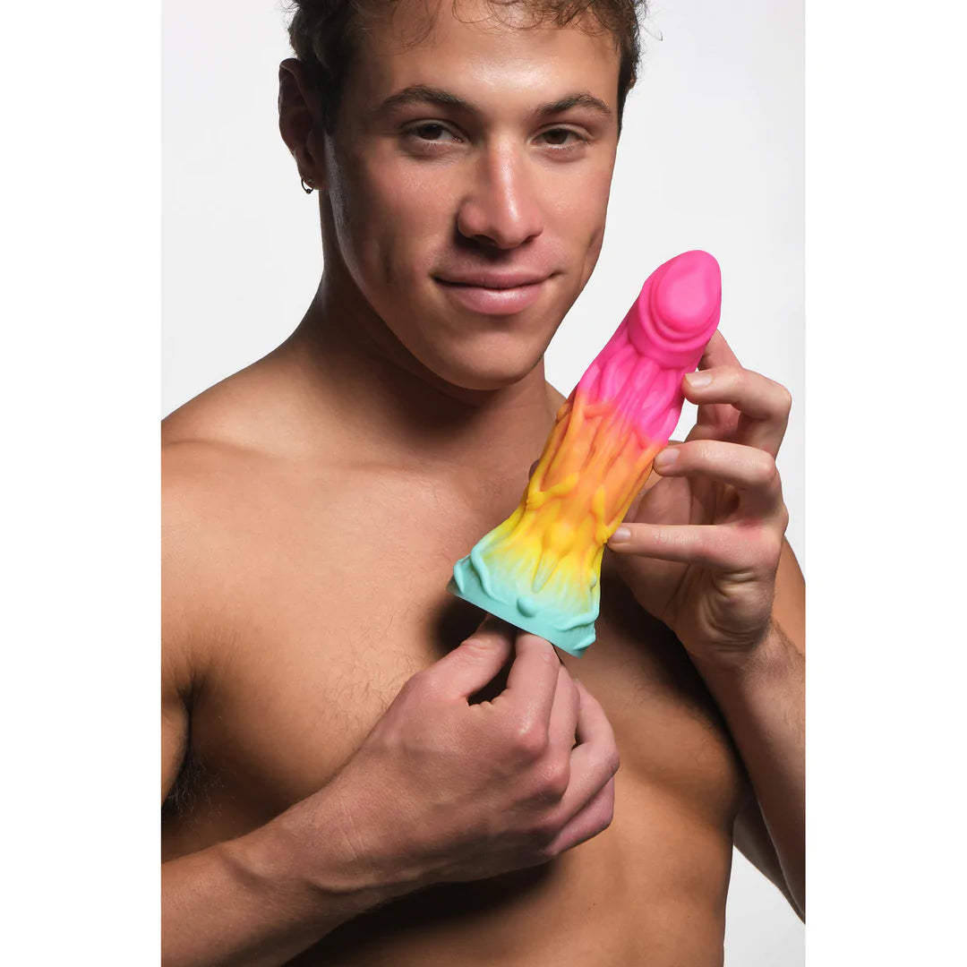 Mann holder en regnbuefarget Shape Shifter Alien Fantasy Dildo med årete kropp og øgleansikt.