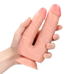 Realistisk flesh-farget dobbeldildo med to peniser (12,7 og 15,2 cm) og sugekoppbase, holdt i en hånd.