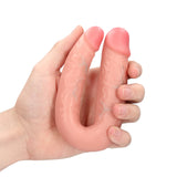 Kjøttfarget U-formet dobbeldildo i realistisk design med årer, holdt i en hånd.