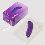 We-Vibe Melt 2 lilla lufttrykksvibrator, eske, ladekabel og oppbevaringspose på en lys bakgrunn.
