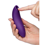 Hånd holder en lilla, ergonomisk We-Vibe Melt 2 lufttrykksvibrator i silikon med en åpen tupp.