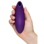 Hånd holder en lilla, oval We-Vibe Melt 2 lufttrykksvibrator med glatt silikonoverflate og åpen tupp.
