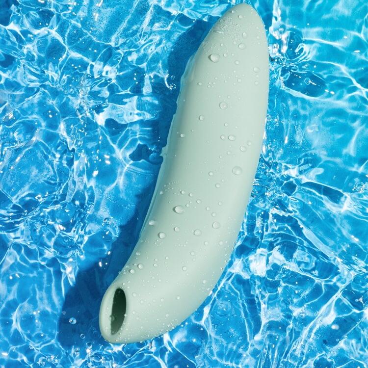 We-Vibe Melt 2 lufttrykksvibrator i dus grønn silikon, dekket av vanndråper på blått vann.